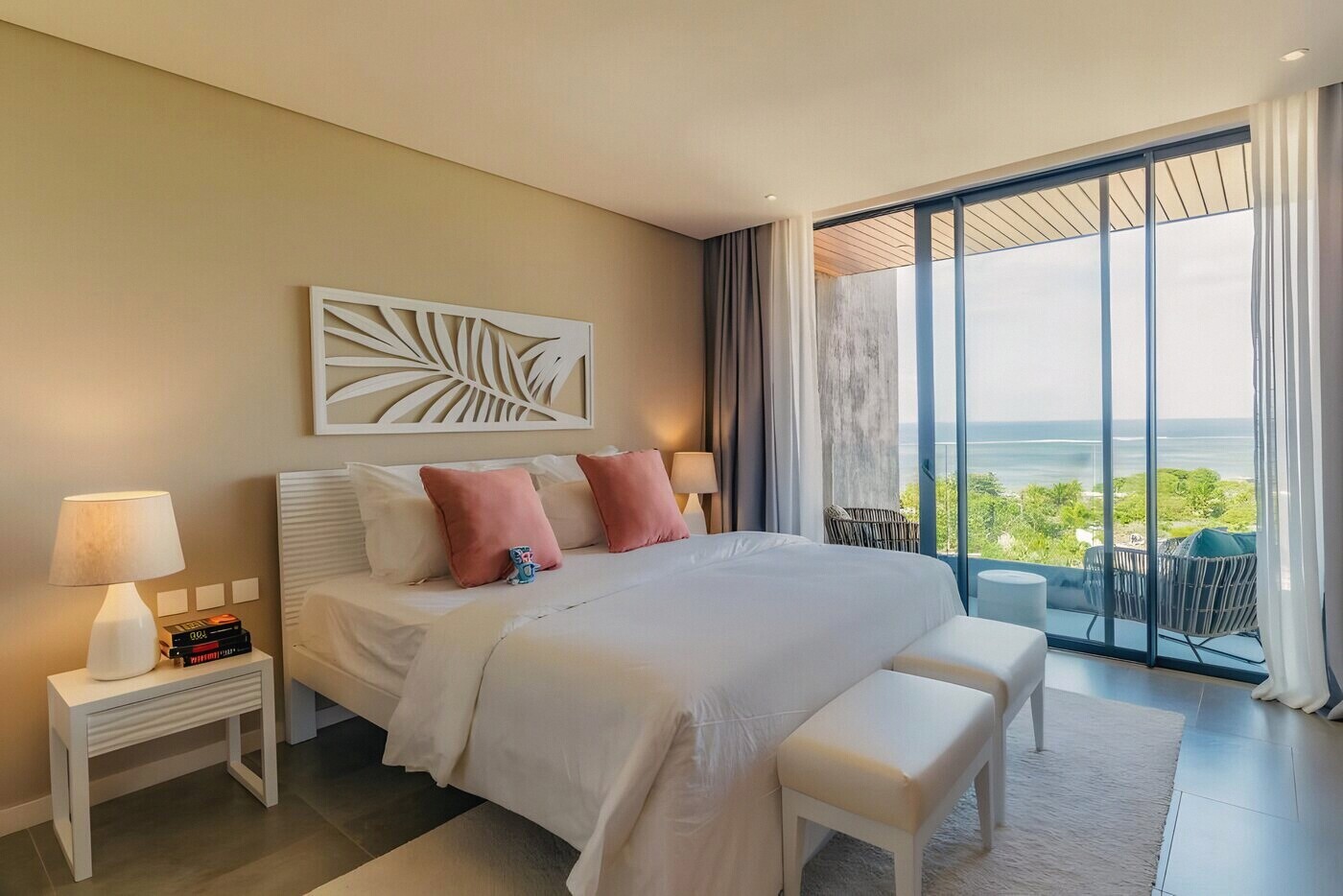 A bedroom with a glass wall onto its own stretch of terrace and the sea