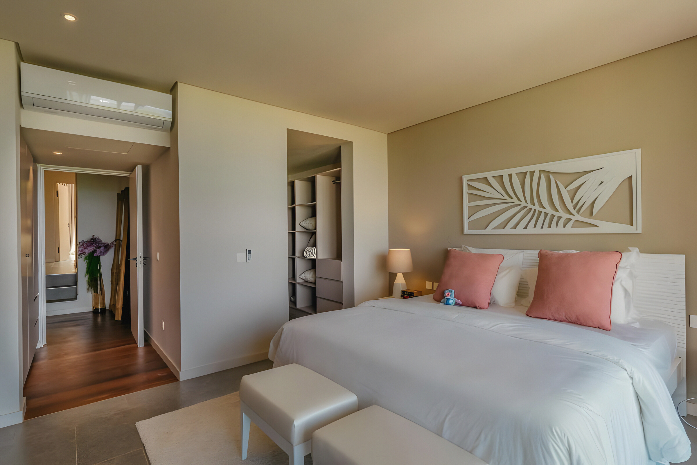 A second bedroom with a carved palm-leaf headboard panel and a walk-through wardrobe