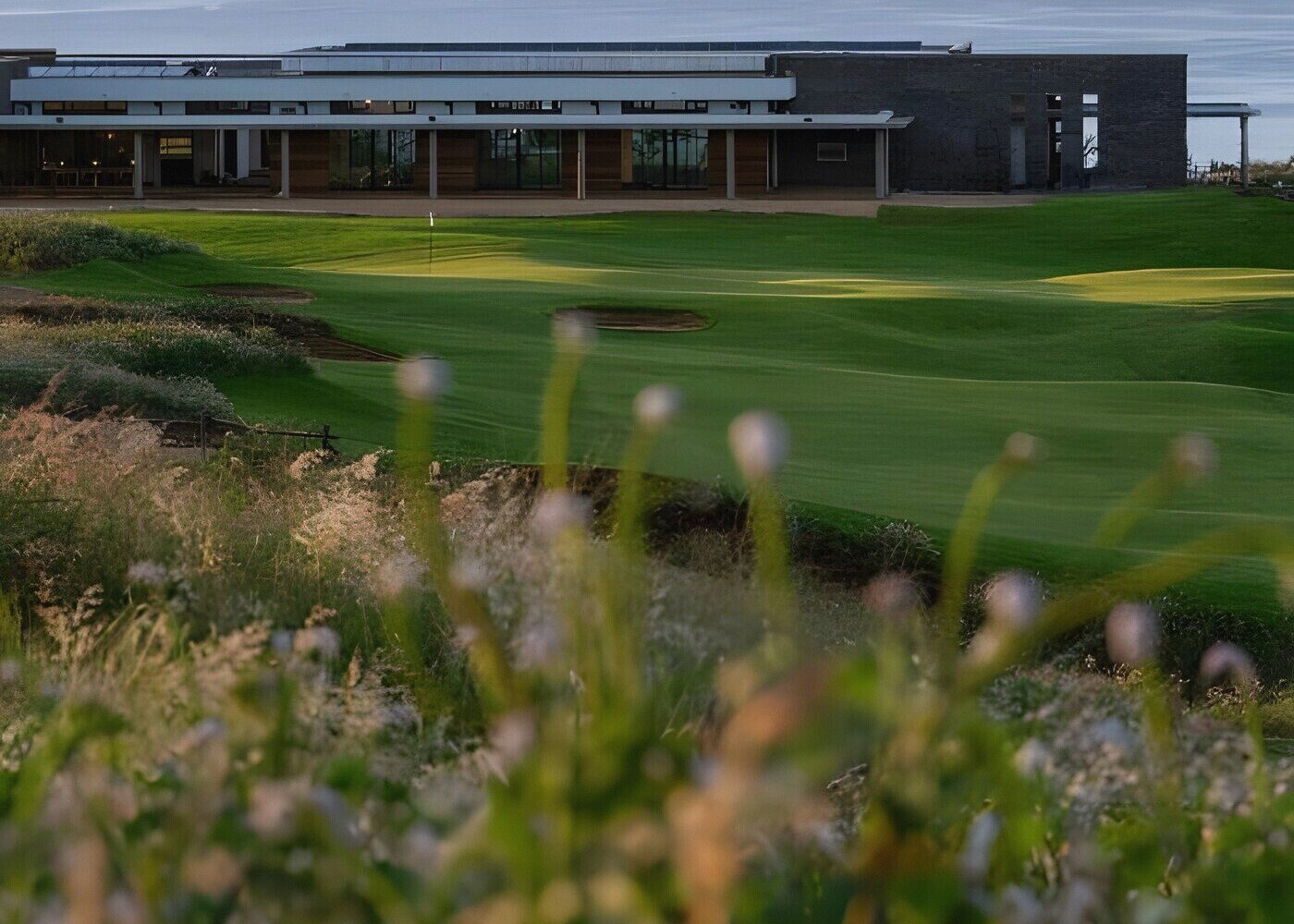 A coastal links course at dusk near the property, the sea beyond the fairway