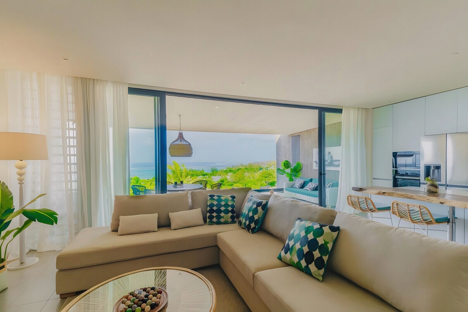 The open-plan living room opening through glass onto the terrace and the sea