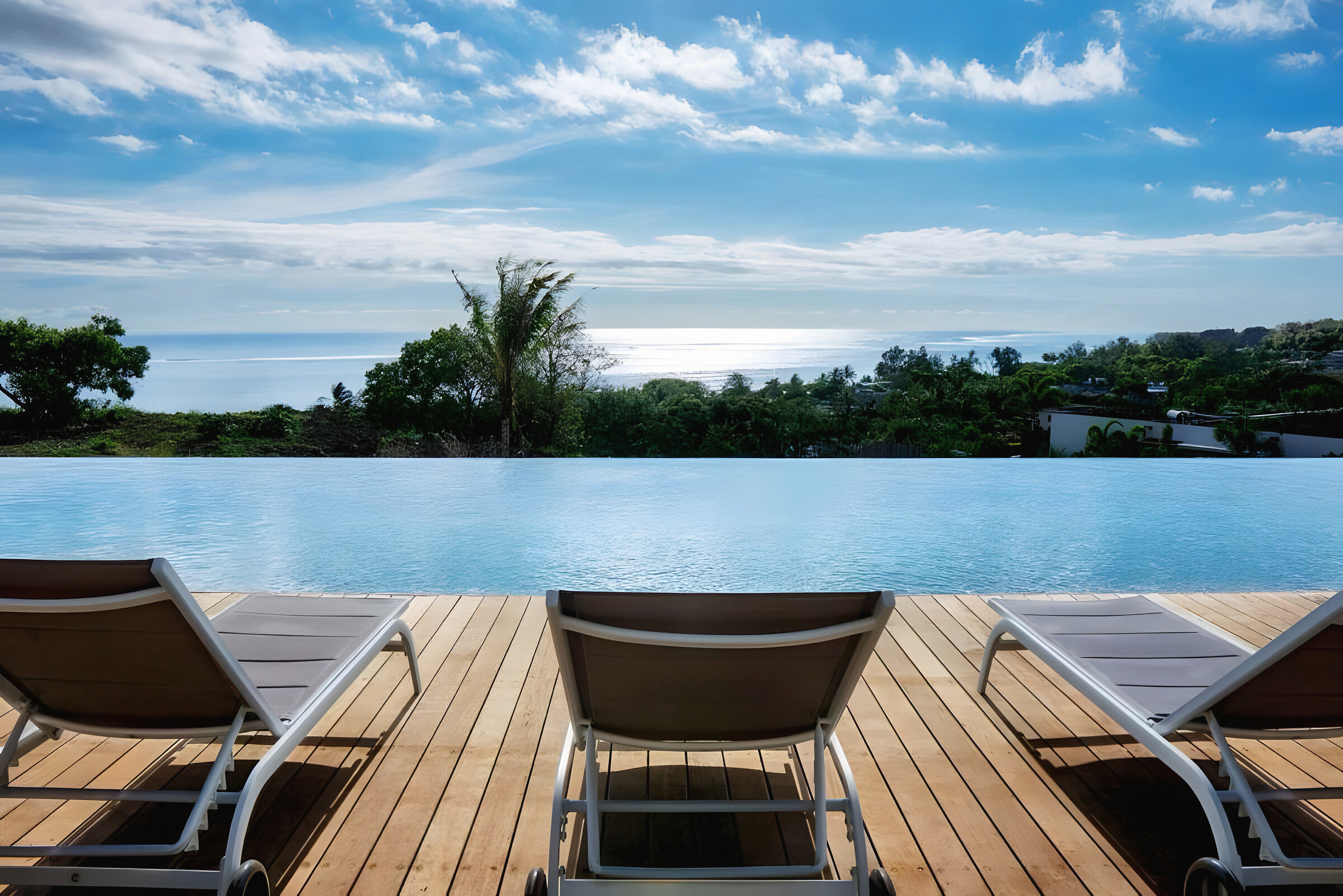 The infinity pool — teak deck, loungers and the sea beyond the pool's edge
