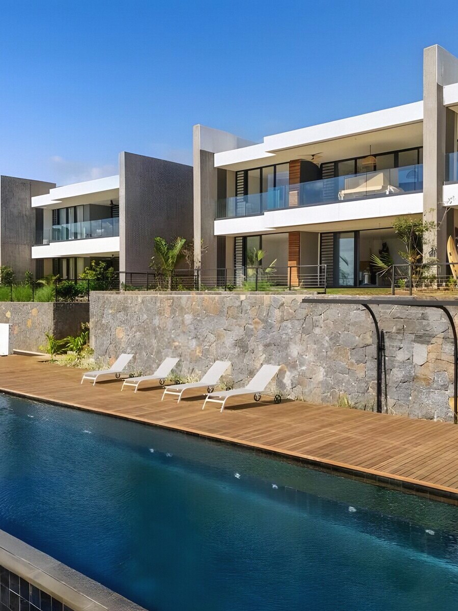 The estate at The View seen from the pool deck — pale concrete, basalt walls, teak decking and the long pool